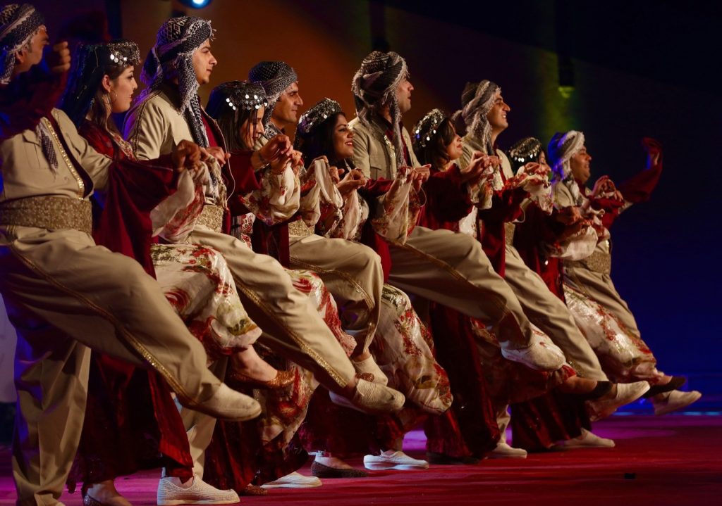 photo showing people in traditional Kurdish dress dancing on stage