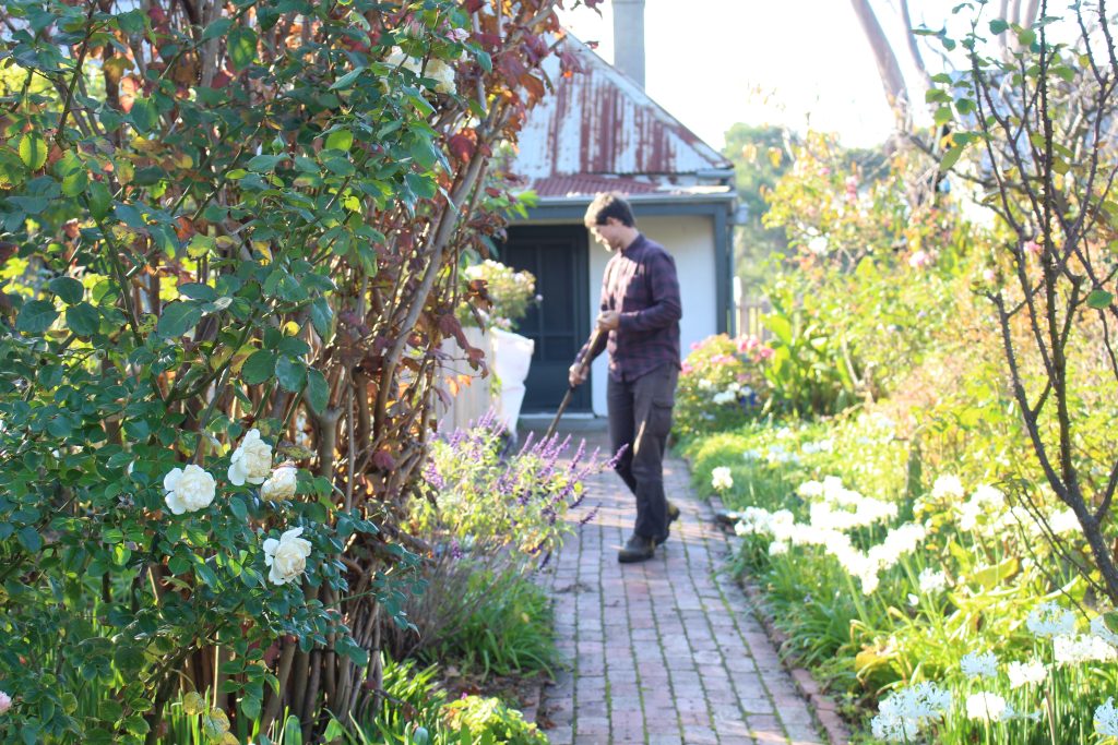 photo of man sweeping in garden and entrance to Ziebell's farmhouse